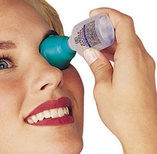 A person is using the EZY eye drop guide with a bottle of eye luibricant.