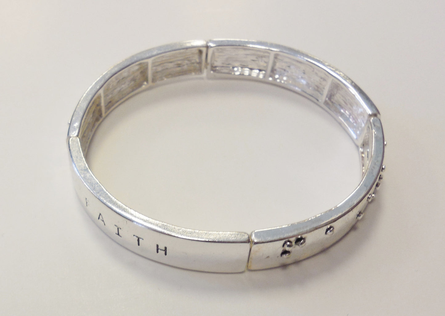 silver bracelet with the word faith in text and braillle