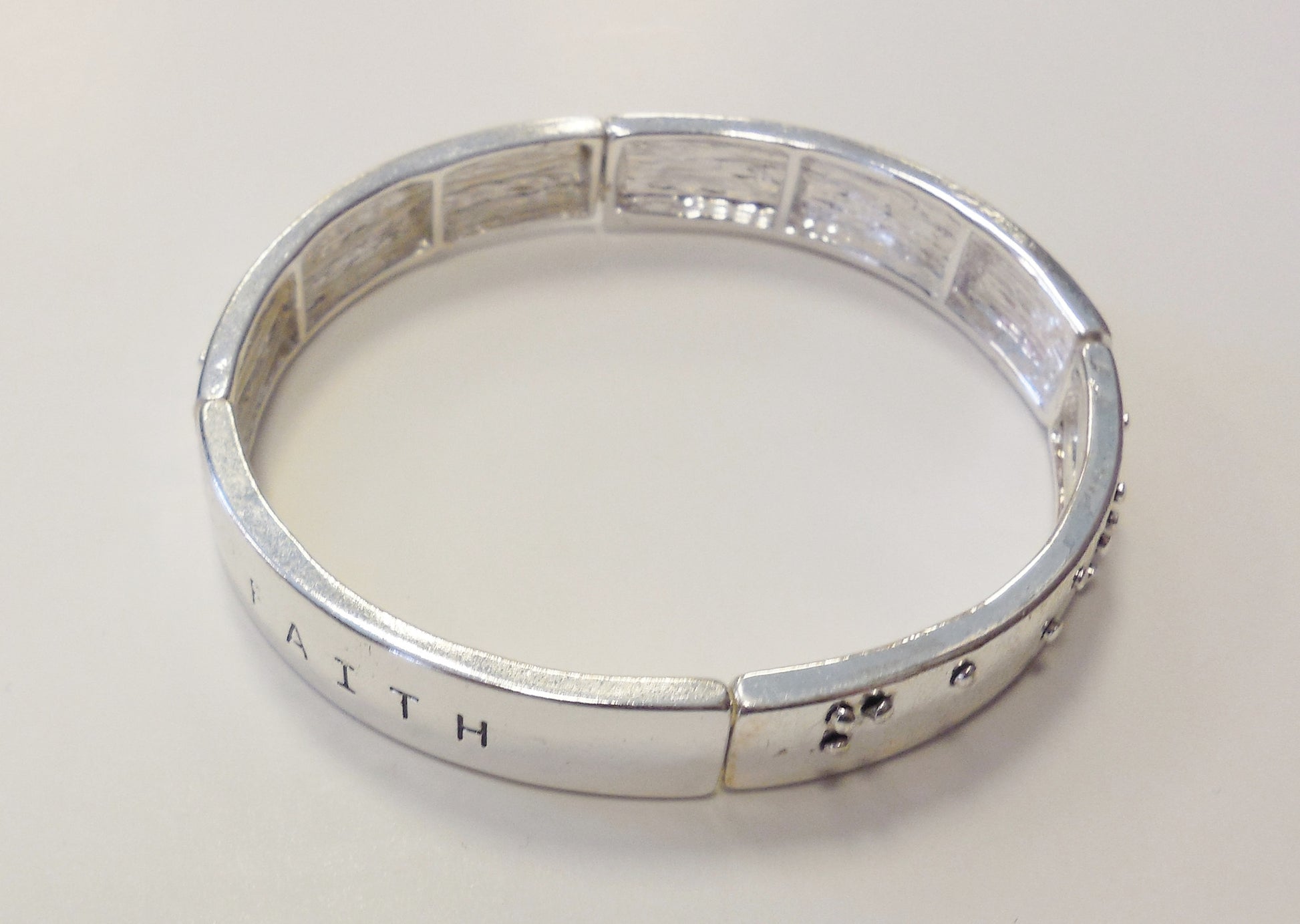 silver bracelet with the word faith in text and braillle